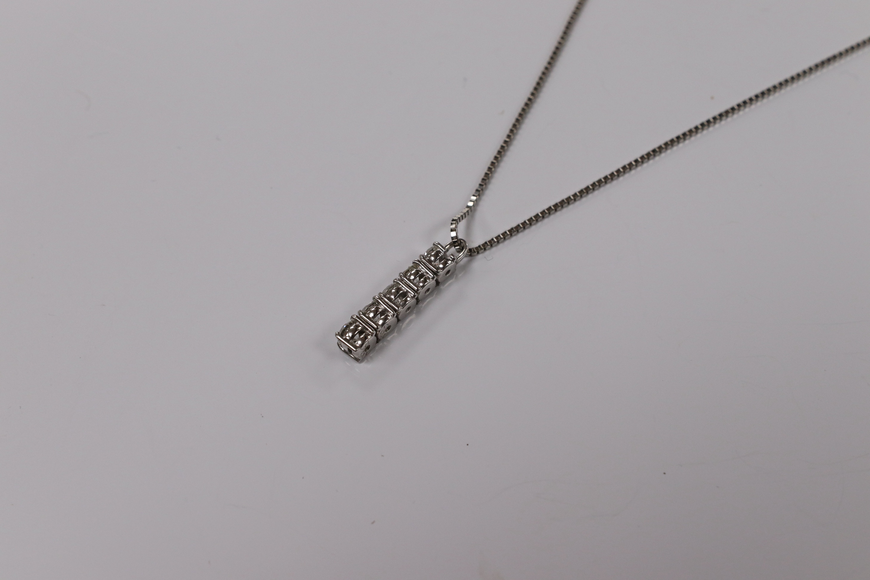 A modern white metal (stamped PT900) and five stone diamond set line pendant, on white metal (stamped pt850), overall 49cm, gross weight 4.9 grams. Condition - fair to good